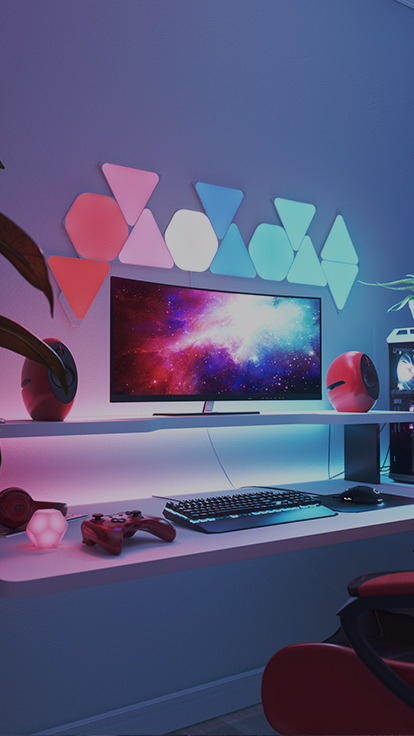 This is an image of Nanoleaf Shapes light panels in a gaming room. They are RGB lights that are perfect for the gamer in your home environment. The modular color-changing light panels connect together to create a design right above the monitor that has Hexagons and Triangles.