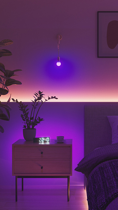 Voici une image d’ampoule Nanoleaf Essentials dans une chambre. Le luminaire est monté sur le mur entre le lit et la table de nuit, et convient parfaitement à la chambre pour créer une ambiance idéale.