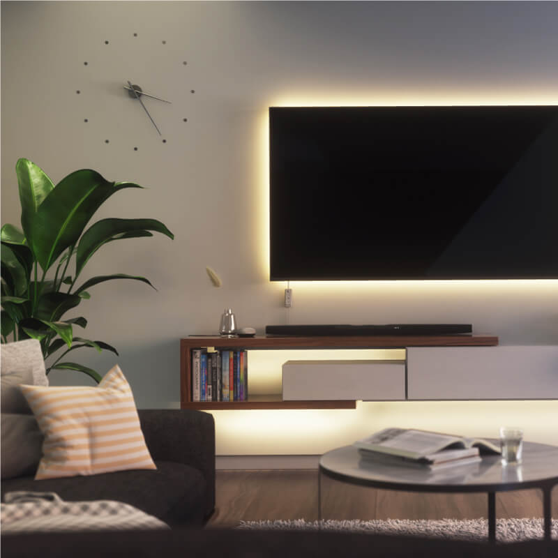 Nanoleaf Essentials Thread enabled color changing smart light strip mounted to a TV in a living room. Similar to Twinkly, Wyze. HomeKit, Google Assistant, Amazon Alexa, IFTTT.