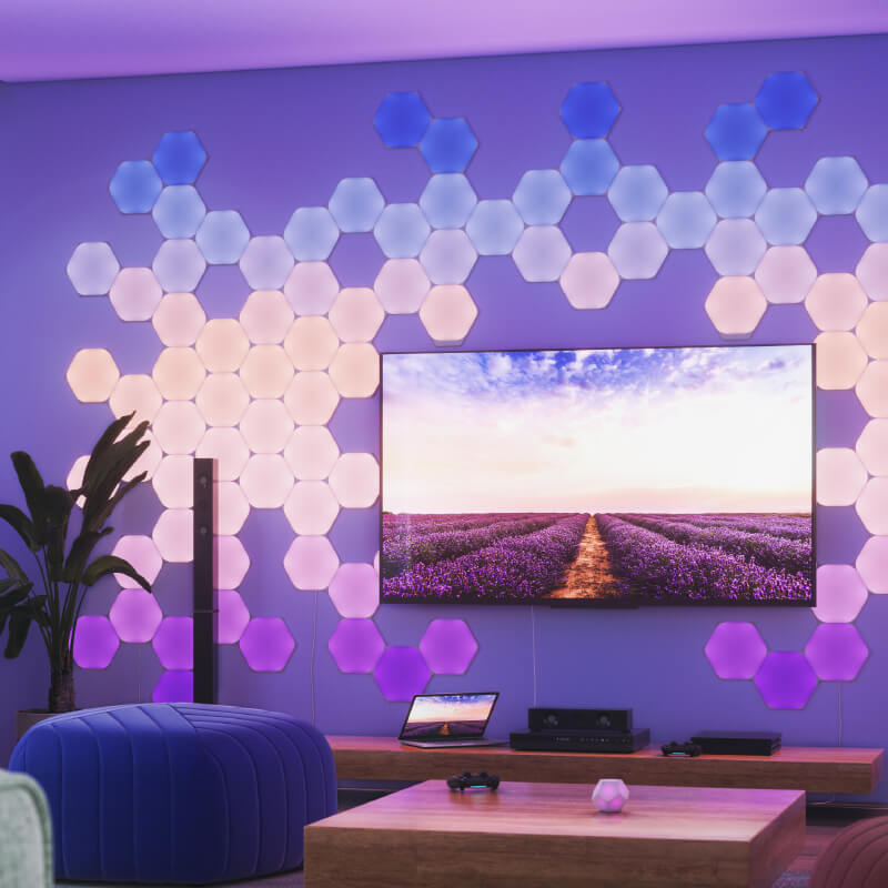 Panneaux lumineux modulaires intelligents Hexagones aux couleurs changeantes et fil compatible Nanoleaf Shapes, montés sur un mur de salon. Produit semblable à Philips Hue, Lifx. HomeKit, Google Assistant, Amazon Alexa, IFTTT.