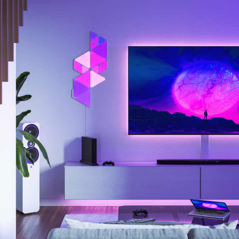 Panneaux lumineux modulaires intelligents Mini triangles aux couleurs changeantes et fil compatible Nanoleaf Shapes, montés sur un mur de salon. Produit semblable à Philips Hue, Lifx. HomeKit, Google Assistant, Amazon Alexa, IFTTT.