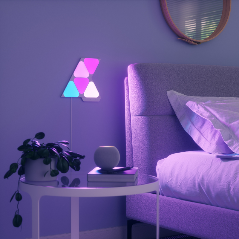 Panneaux lumineux modulaires intelligents Mini triangles aux couleurs changeantes et fil compatible Nanoleaf Shapes, montés sur un mur de chambre à coucher. Produit semblable à Philips Hue, Lifx. HomeKit, Google Assistant, Amazon Alexa, IFTTT.