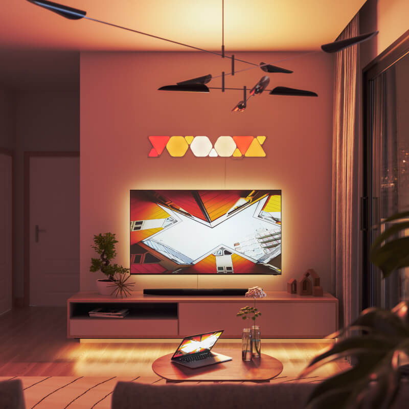 Panneaux lumineux modulaires intelligents Triangles aux couleurs changeantes et fil compatible Nanoleaf Shapes, montés sur un mur de salon. Produit semblable à Philips Hue, Lifx. HomeKit, Google Assistant, Amazon Alexa, IFTTT.
